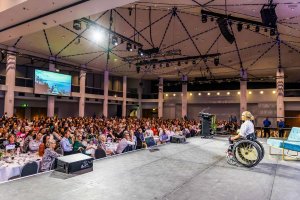 Sam Bloom Speaker On Stage to large Crowd